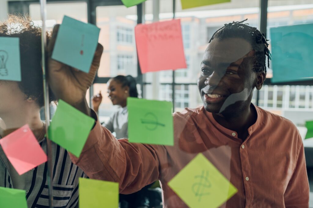 Multiracial team at work writing ideas on sticky notes on the glass wall